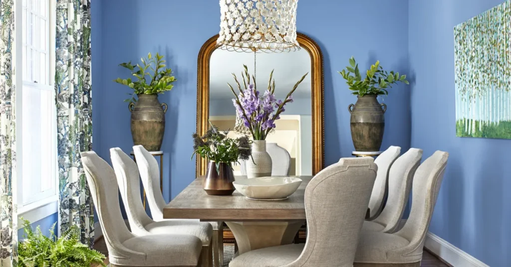 A modern dining room with a navy accent wall, warm wood dining table, soft pendant lighting, and neutral décor showcasing elegant dining room paint color inspiration.