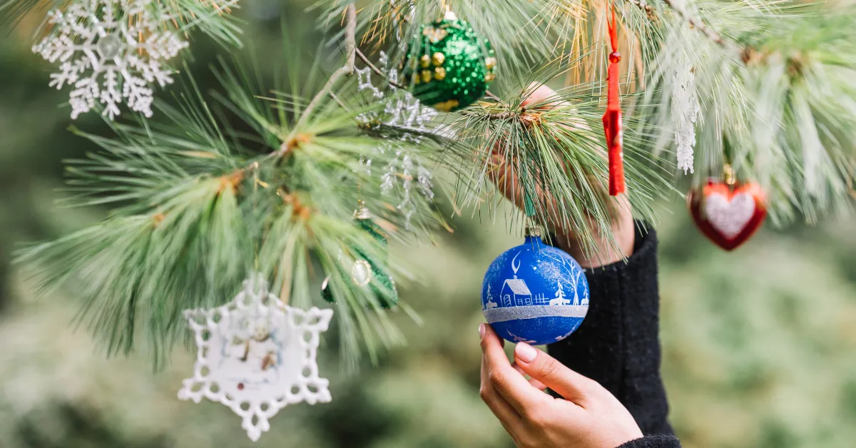 Hand hanging ornament on Christmas tree branch, Christian Elf on the Shelf Ideas theme display setup
