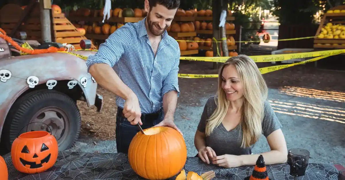 pumpkin carving ideas using drill with couple carving pumpkin at outdoor fall market table