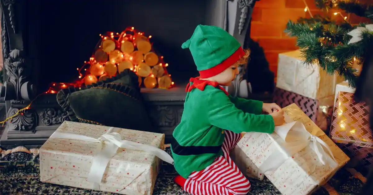 Child dressed as elf opening gifts by fireplace and tree, christian elf on the shelf ideas scene