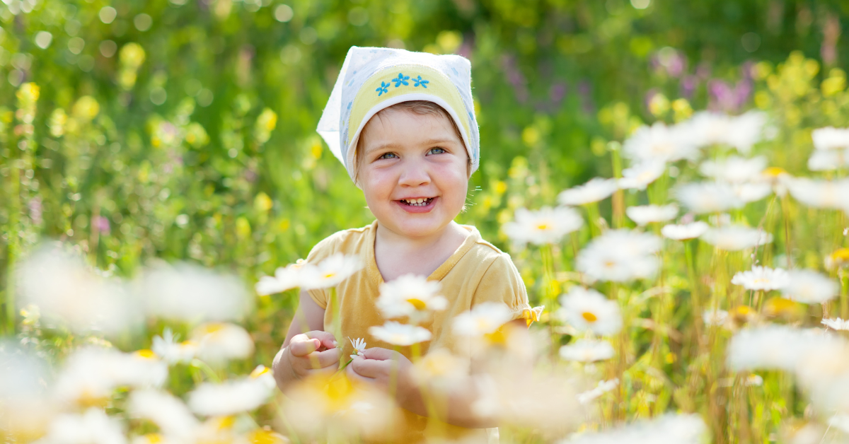 Elf on the shelf ideas for toddlers with smiling child in flower field on sunny day outdoors.