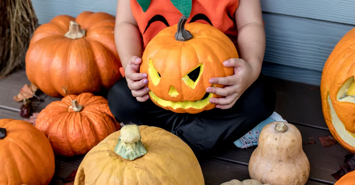 pumpkin carving ideas funny child holding jack o lantern with playful spooky face on porch display