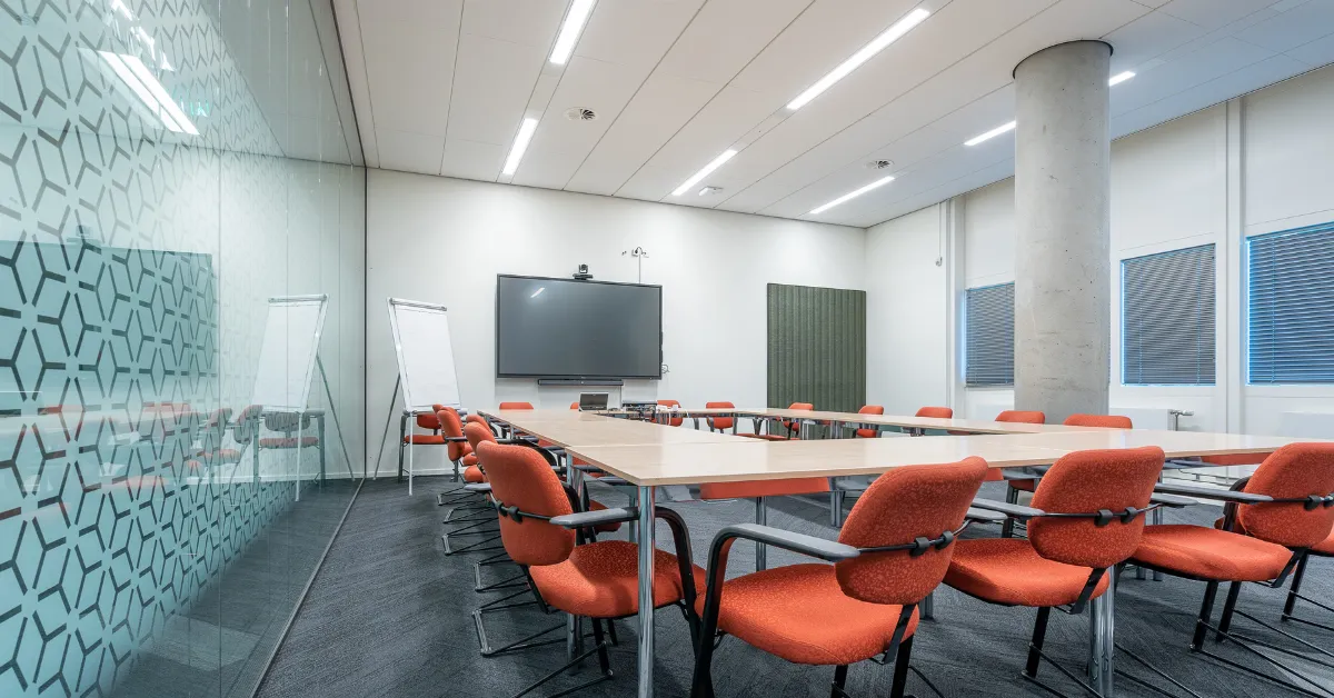 elf on the shelf ideas for office in modern meeting room with table, chairs, and screen display.