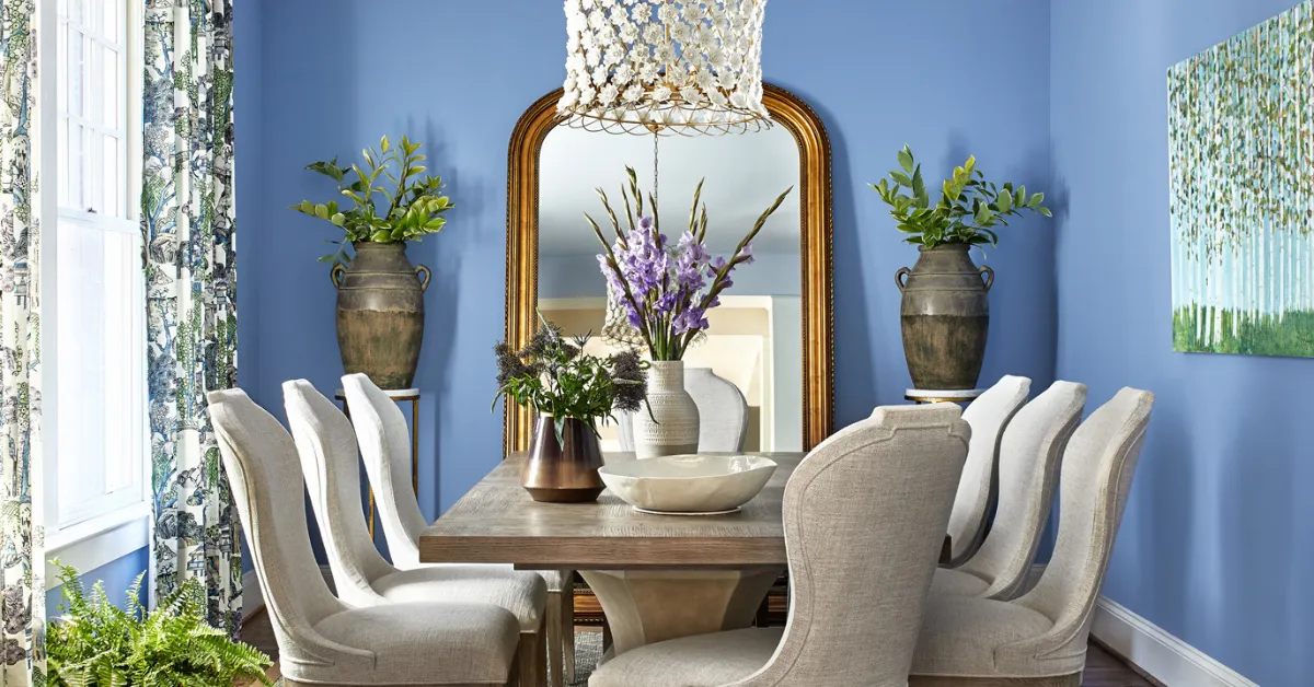A modern dining room with a navy accent wall, warm wood dining table, soft pendant lighting, and neutral décor showcasing elegant dining room paint color inspiration.
